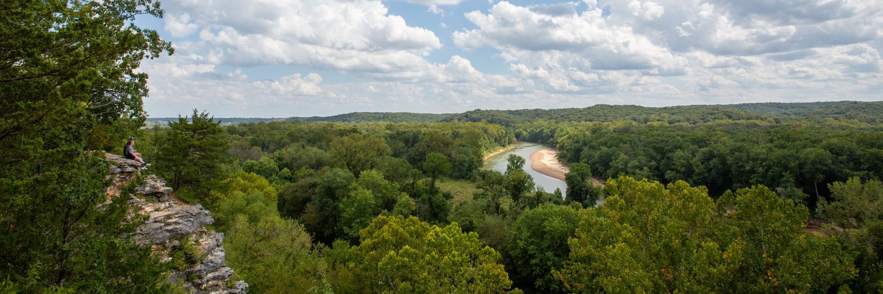 Hikers perch on a limestone bluff overlooking a river at Castlewood State Park.