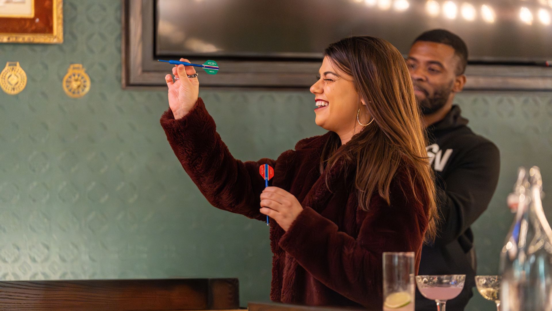 A woman closes one eye as she throws darts at Flight Club in St Louis.
