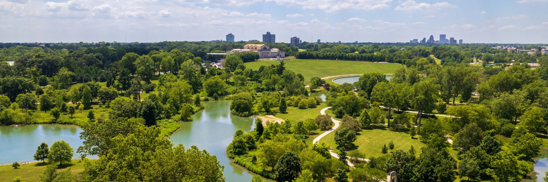 A drone shot shows the greenery and waterways of Forest Park with the Saint Louis Art Museum in the background.