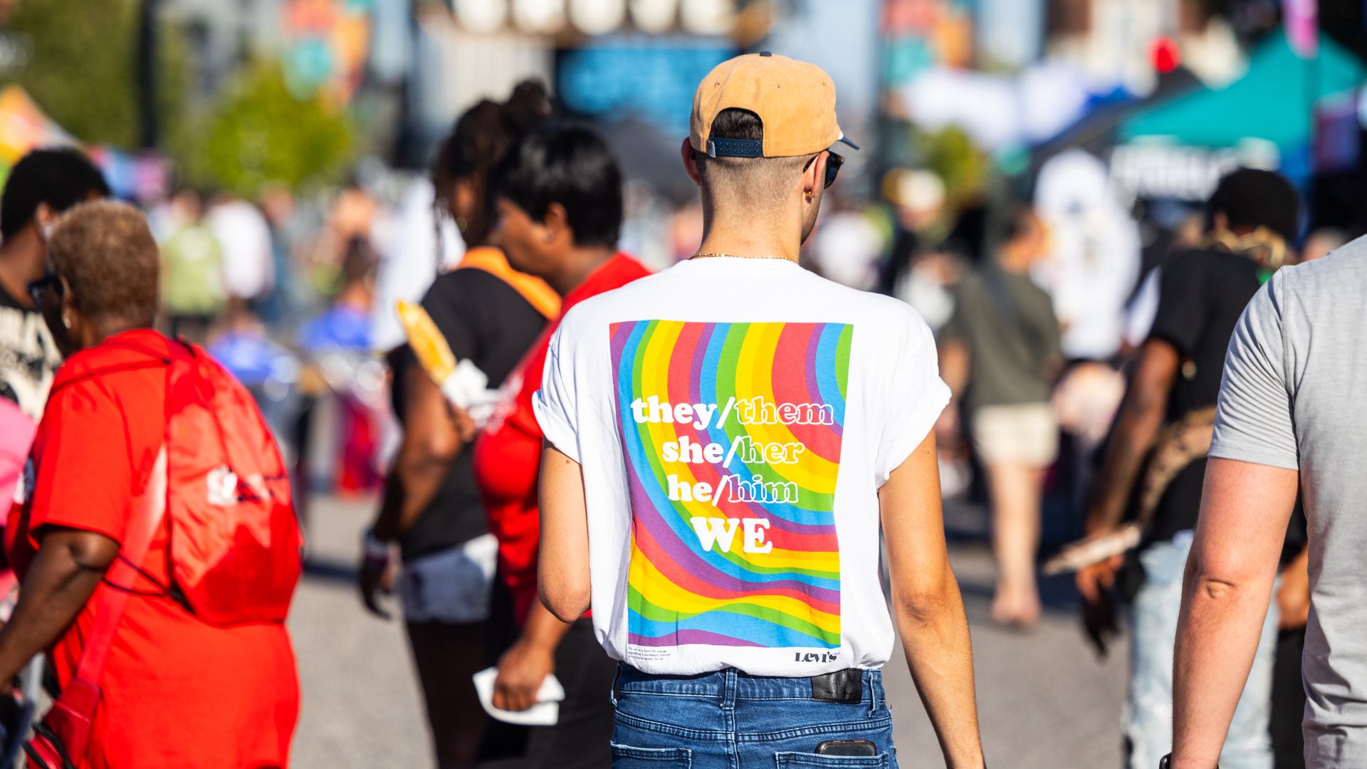 A man's shirt reads they/them she/her he/him we.