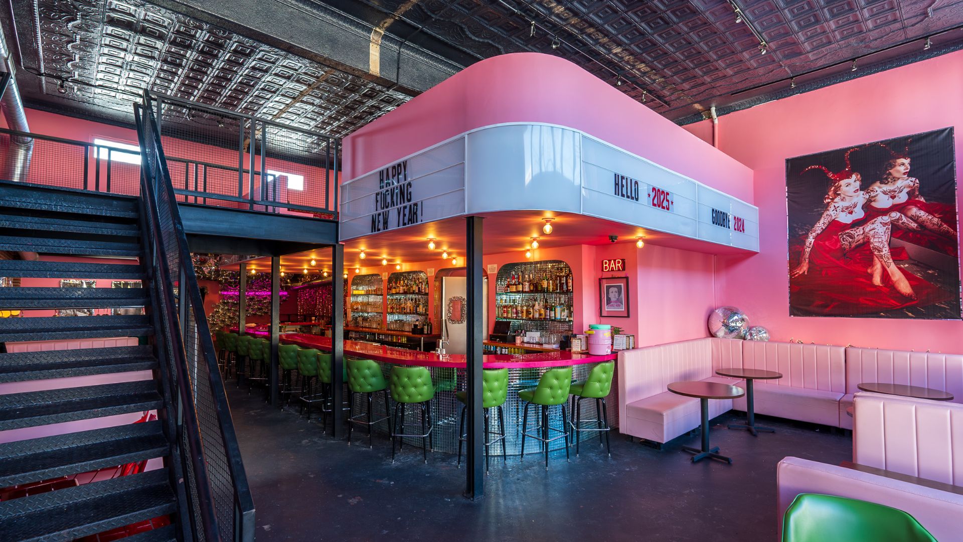 A disco dive bar in St Louis features pink walls, green barstools and feminine wall art.