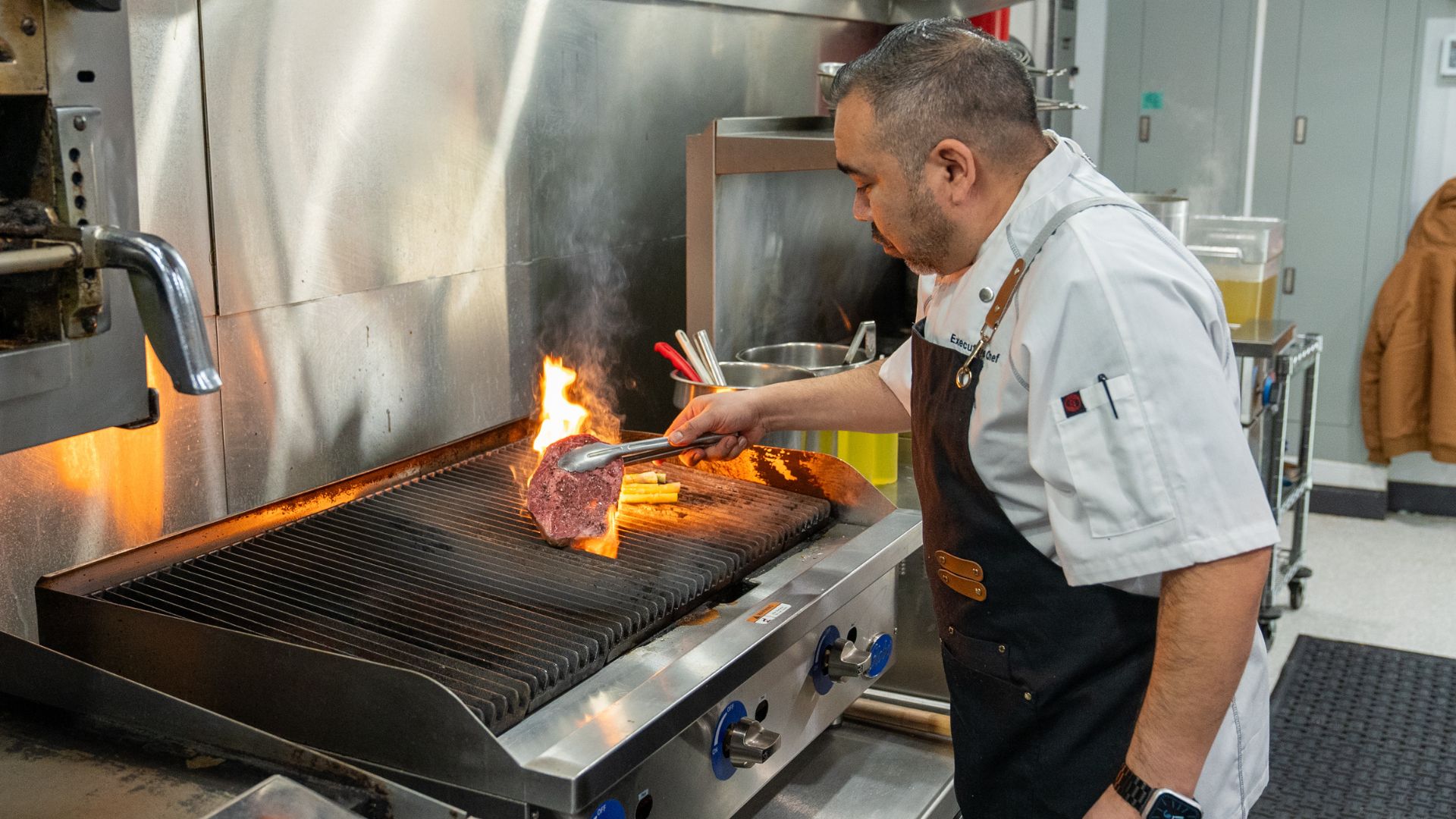 Chef Carlos Hernandez cooks Wagyu rib eye over an open flame in the kitchen of Marconi Mercato.