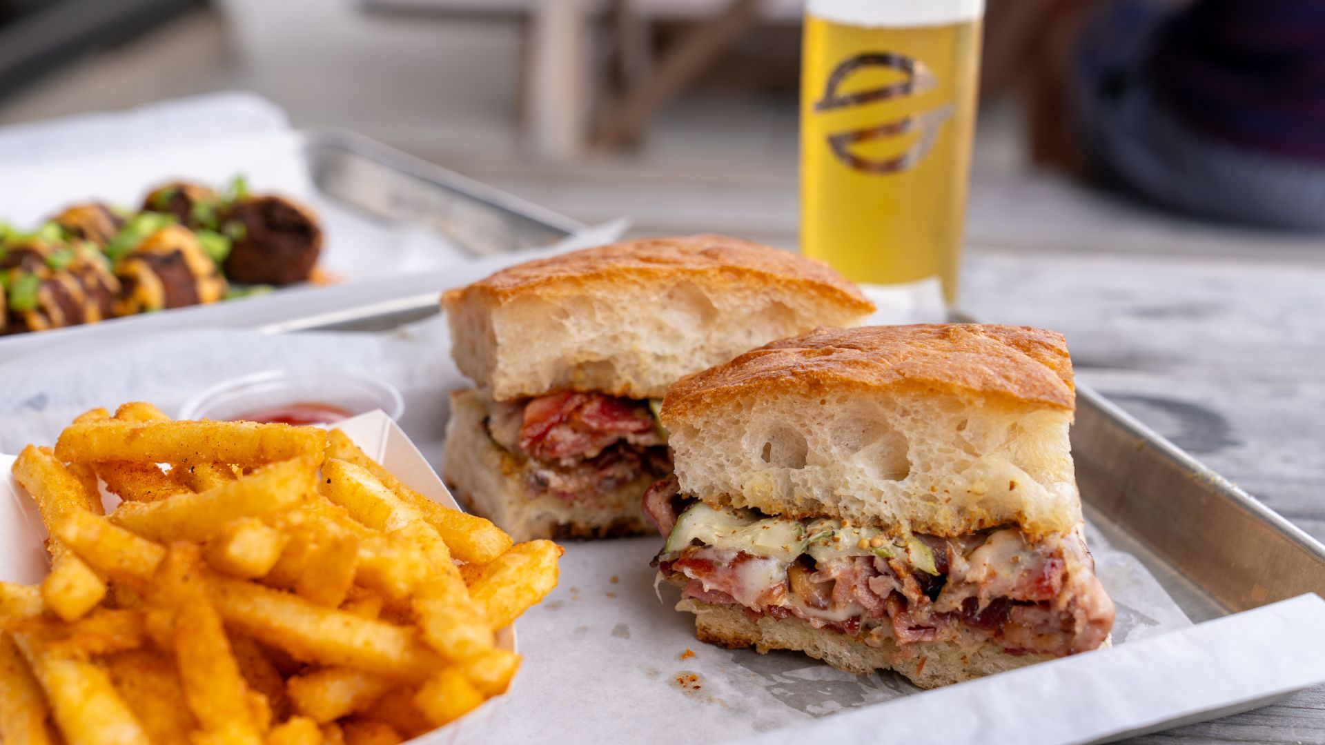 Modern Brewery serves a porchetta pastrami sandwich and fries alongside a local craft beer.