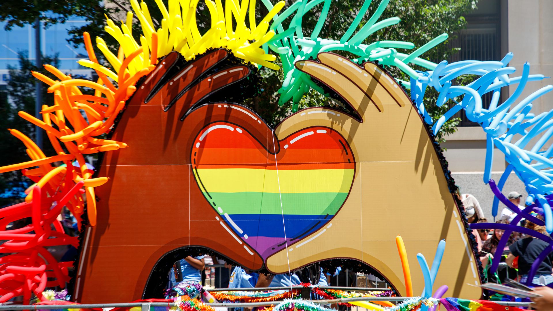 At PrideFest in St. Louis, a float shows hands making a heart surrounding by colorful balloons.