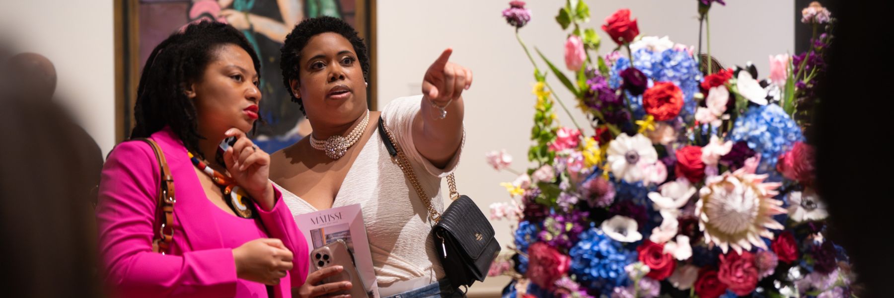 Well-dressed friends admire a bouquet of flowers during Art in Bloom at the Saint Louis Art Museum.