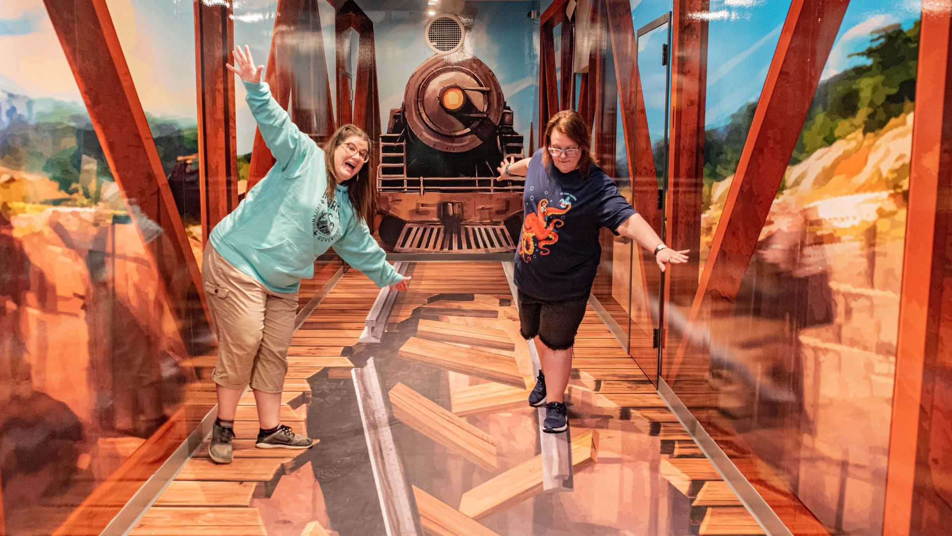 Two women pretend to fall off a bridge in the Selfie Express.