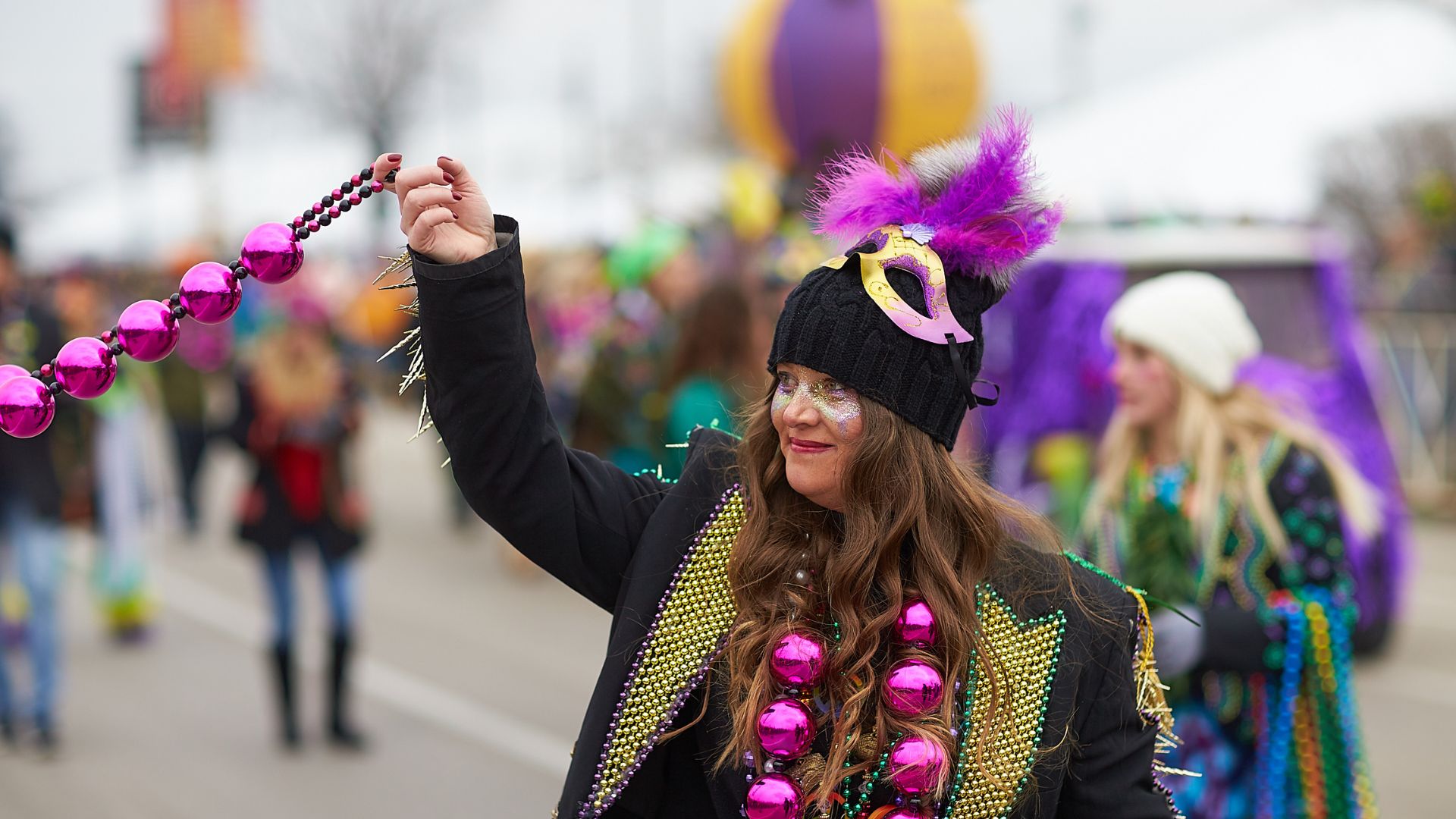 A woman throws beads at Soulard Mardi Gras.