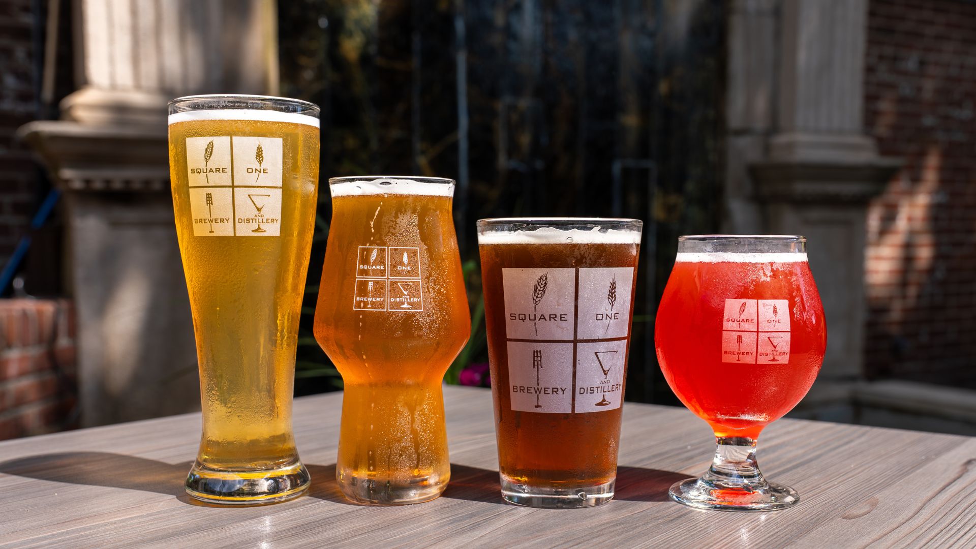 Four differently hued beers line a table on the patio of Square One Brewery and Distillery in St Louis' Lafayette Square.