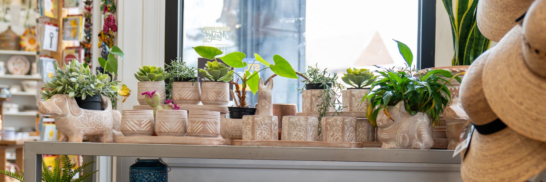 A shelf holds terracotta planters in the shape of dogs, cats, chickens, elephants and llamas.